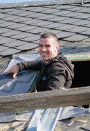 glücklicher Dachdecker von Bedachungen Schmidt bei arbeiten mit einem Faserzementschiefer